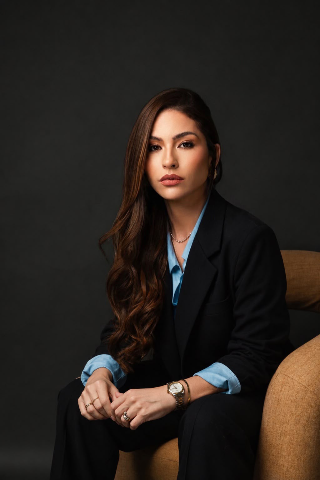 Dra. Stephany Quintanilha sentada, em retrato de estúdio com blazer preto